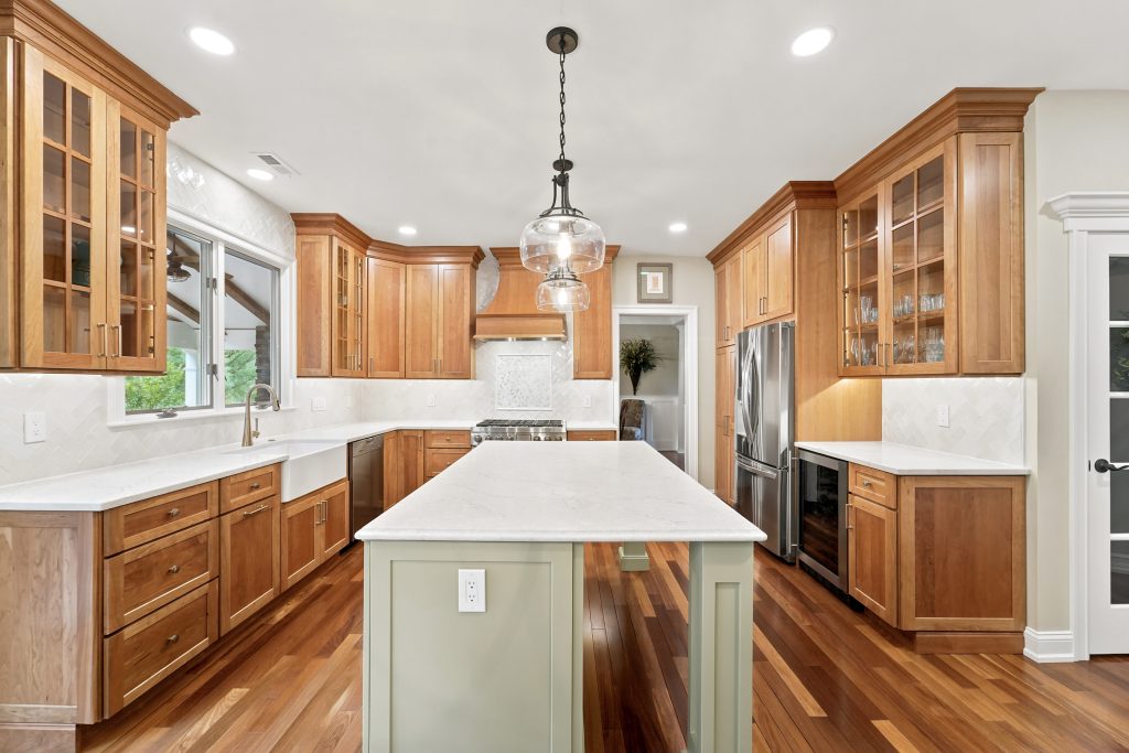 Two-tone old-world kitchen with cherry cabinets and a sage green island in a Phoenixville PA remodel by Majestic Home Renovations