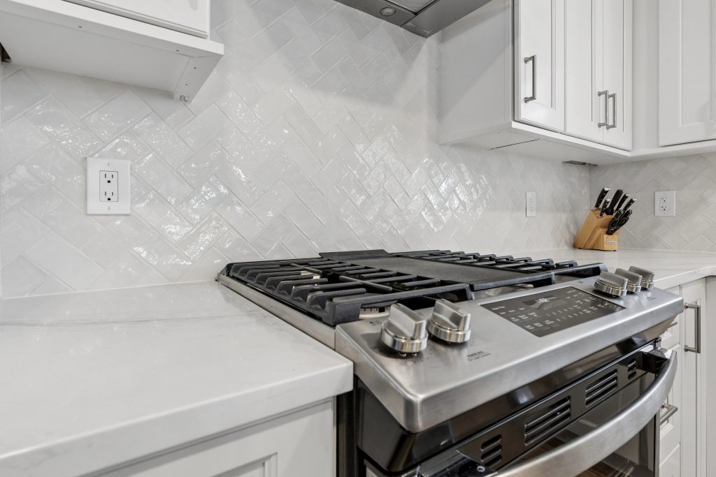 White Fabuwood Allure Fusion cabinets with herringbone backsplash and stainless range in Royersford PA kitchen renovated by Majestic Home Renovations