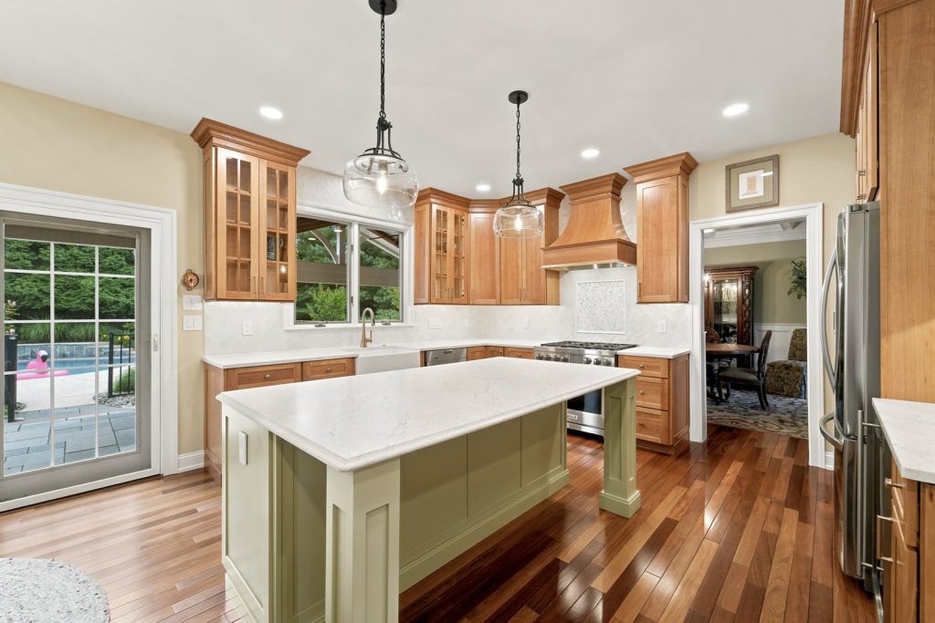 Two-tone kitchen remodel in Phoenixville, PA with a sage green island, cherry cabinets, and white quartz countertops by Majestic Home Renovations.