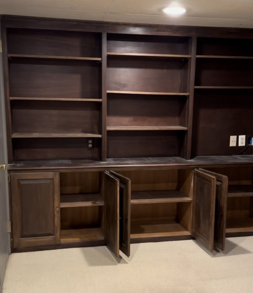 Dark built-in shelving in a basement before renovation by Majestic Home Renovations
